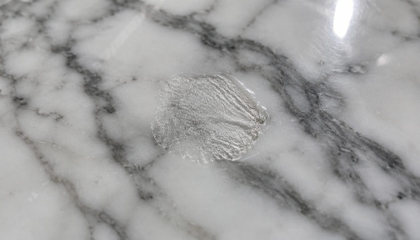 Close-up of a dull etch mark on polished white marble